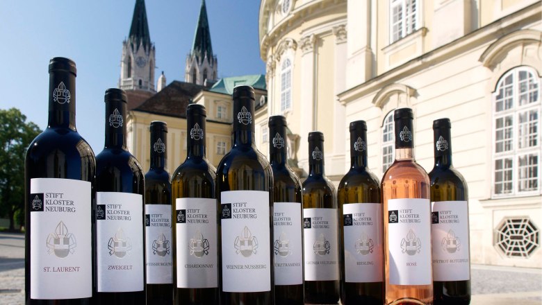 Stift mit Klassikwein Sortiment, © Stift Klosterneuburg - Michael Zechany Weinflaschen des Stift Klosterneuburg vor einem historischen Gebäude.