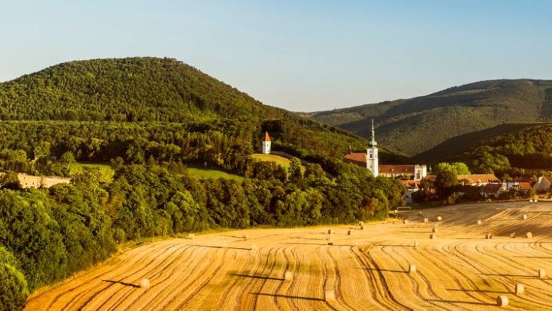 Stift Heiligenkreuz, © Niederösterreich-Werbung/Michael Liebert Panorama des Stifts Heiligenkreuz mit umliegenden Feldern und Hügeln.