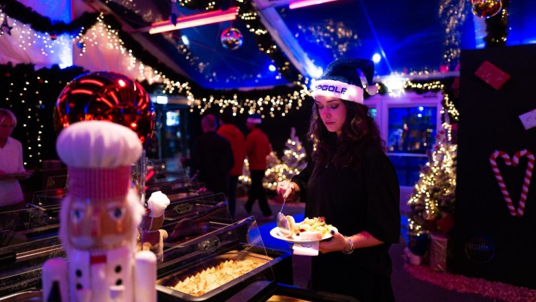 Festliche Genussmomente in stimmungsvoller Atmosphäre, © Topgolf Wien Stimmungsvoll beleuchtetes Winterevent bei Topgolf mit festlicher Dekoration, Weihnachtslichtern und Buffet in gemütlicher Weihnachtsatmosphäre.