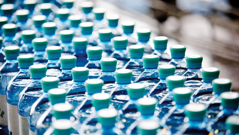 Vöslauer Mineralwasser, © Vöslauer Reihen von Vöslauer Mineralwasserflaschen mit grünen Verschlüssen.