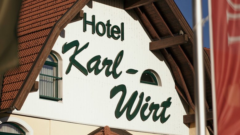 Fassade des Hotels Karl-Wirt mit rotem Dach und grünen Fensterläden.