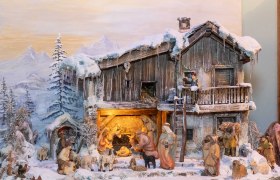 Weihnachtliche Krippenszene mit Figuren in einer verschneiten Landschaft.