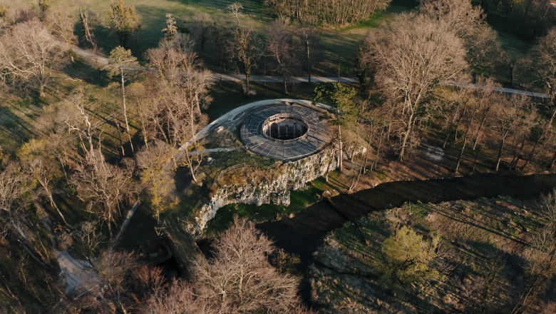Luftaufnahme eines runden Geb&auml;udes in einem Waldgebiet.