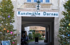 Eingang zur Kunstm&uuml;hle Dornau mit dekorativen Elementen und Pflanzen.