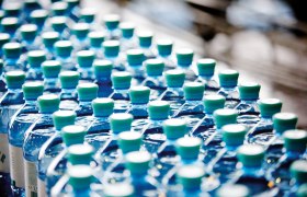 Reihen von Vöslauer Mineralwasserflaschen mit grünen Verschlüssen.