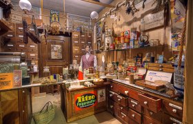 Ein historischer Tante-Emma-Laden mit alten Produkten und einer Schaufensterpuppe.