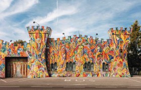 Bunt bemalte Fassade eines Gebäudes in Form einer Burg mit Türmen.