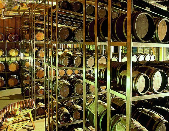 Innenansicht einer Kellerei mit vielen Holzf&auml;ssern auf Regalen.